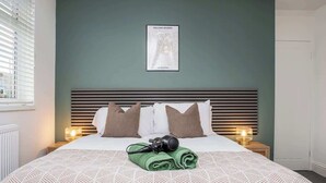 Ein Hotelzimmer mit Bett, Kissen, einem gerahmten Bild an der Wand und einer Kamera auf dem Bett.