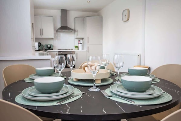 A dining area with a round table set for four, surrounded by chairs.