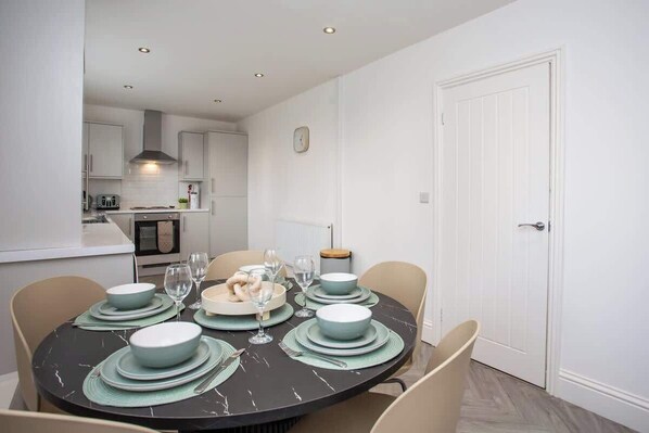 A dining area with a round table set for four, surrounded by chairs.