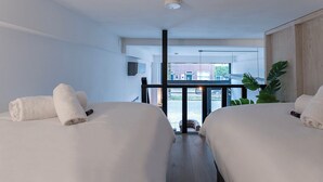 Une chambre d’hôtel avec deux lits, une grande fenêtre et une vue sur l’extérieur.