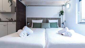 Una habitación de hotel con dos camas, techo de madera, una ventana y una planta.