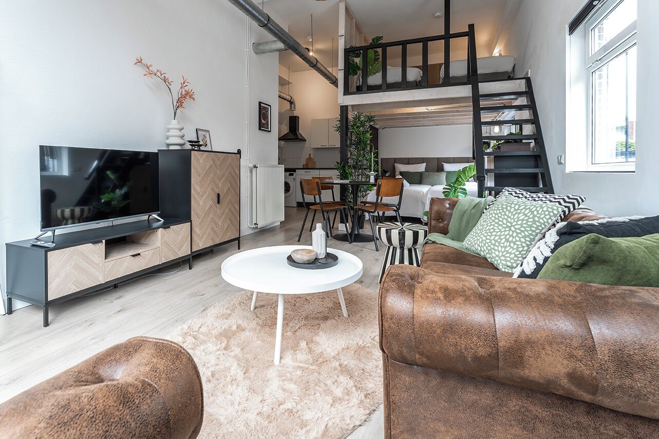 Ein modernes Wohnzimmer mit Fernseher, Sofa, Couchtisch und einer Essecke mit Stühlen und Tisch.