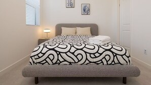 A bedroom with a bed, a nightstand, a lamp, and two wall art pieces. - Near ONT Modern Designer Stay Bright Chic Spacious (Ontario)