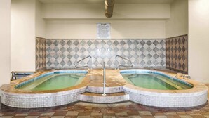 Ein Wellnessbereich mit zwei Whirlpools und einer gefliesten Wand.