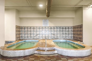Ein Wellnessbereich mit zwei Whirlpools und einer gefliesten Wand.