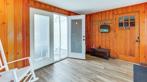 Una habitación con paredes de madera, un ventanal corredero, un banco y una puerta con un letrero.