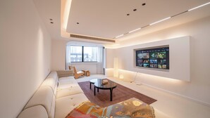 A modern living room with a sofa, a coffee table, and a flat-screen TV mounted on the wall. - Book and Bed - Xujiahui (Shanghai)