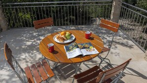 A round wooden table with four metal chairs, a plate with food and drinks, and a magazine. - Holiday Home With Pool Near Makarsk (Proložac)