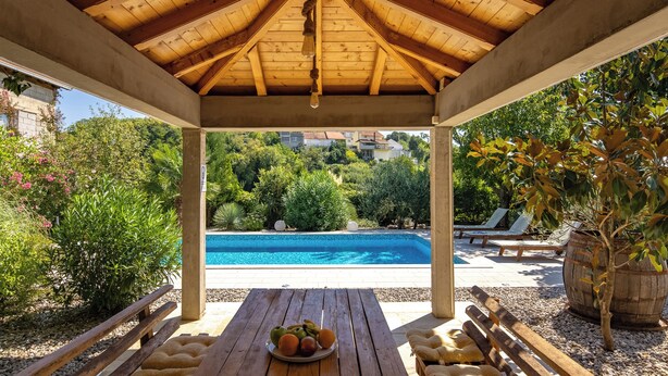 A wooden gazebo with a view of a swimming pool and greenery. - Holiday Home With Pool Near Makarsk (Proložac)