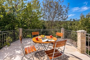 A terrace with a table set for two, surrounded by metal railings, and a stone pillar. - Holiday Home With Pool Near Makarsk (Proložac)