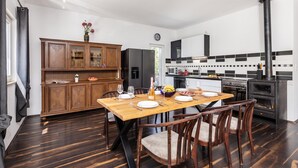 A modern kitchen with a dining area, featuring a wooden cabinet, a refrigerator, a stove, and a dining table set for four. - Holiday Home With Pool Near Makarsk (Proložac)