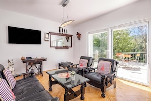 A spacious living room with a large flat-screen TV, leather sofas, a glass coffee table, and a dining area with outdoor seating. - Holiday Home With Pool Near Makarsk (Proložac)