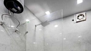 Un baño moderno con inodoro, cabina de ducha y suelo de baldosas.