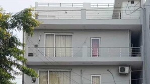 Un edificio de varios pisos con dos autos estacionados frente a él.