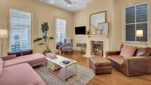 Un salón amplio con chimenea, asientos cómodos y ventilador de techo.