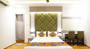 A hotel room with a large bed, a desk with two chairs, a green upholstered headboard, and a tiled floor. - Hotel Gorrion (Mumbai)