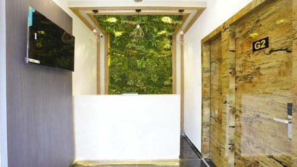 A reception area with a green wall, a wooden door labeled 'G2', and a flat-screen TV on the wall. - Hotel Gorrion (Mumbai)