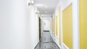 A hallway with white walls, yellow panels, and a reflective floor. - Hotel Gorrion (Mumbai)
