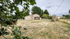 A building with a stone facade, a fenced yard, and trees in the background. - Holiday Home 'La Musardière' with Private Pool, Private Terrace and Wi-Fi (Champagnolles)