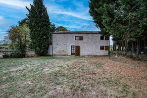 A stone building with a small front yard and tall trees.