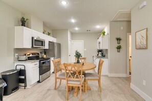 A modern kitchen with white cabinetry, stainless steel appliances, and a wooden dining table with chairs.