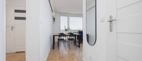 A hallway with a wooden floor leading to a dining area with a table and chairs.