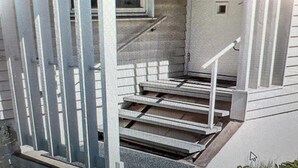 Ein eingeschossiges Haus mit Veranda, sichtbarer Treppe und einer Tür zum Innenbereich.