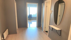 Ein Korridor mit Holzboden, einer Tür zu einem Balkon und einem an der Wand befestigten Regal mit Spiegel.