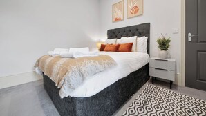 Ein modernes Schlafzimmer mit einem großen Bett, einem Nachttisch und einem Beistelltisch.