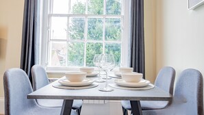 A dining table with four chairs, two wine glasses, and several bowls and plates. - WhiskAwayHomes Shaw Street Apartment 5 (Worcestershire)