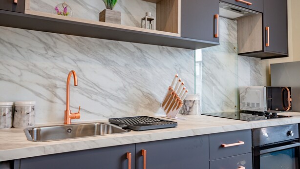 A modern kitchen with a marble backsplash, copper faucet, and built-in appliances. - WhiskAwayHomes Shaw Street Apartment 5 (Worcestershire)