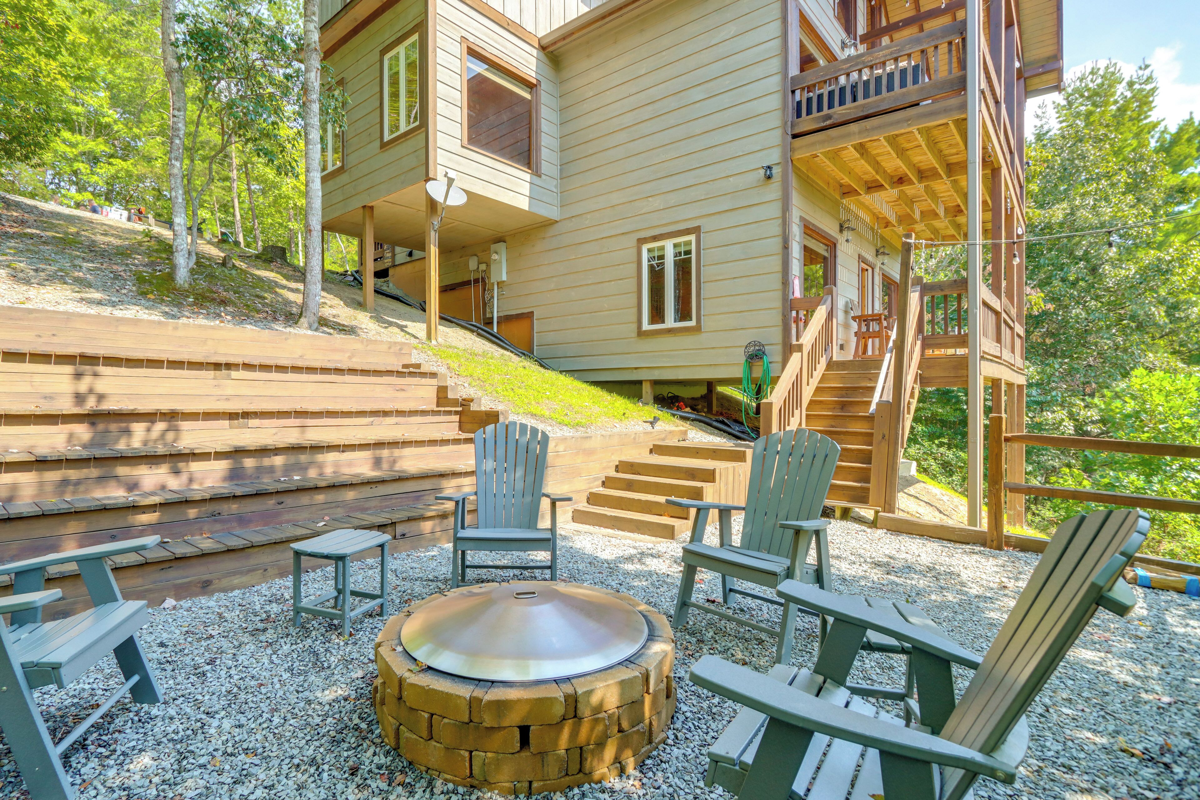 A wooden deck with Adirondack chairs, a fire pit, and a stone staircase leading to a multi-level cabin.