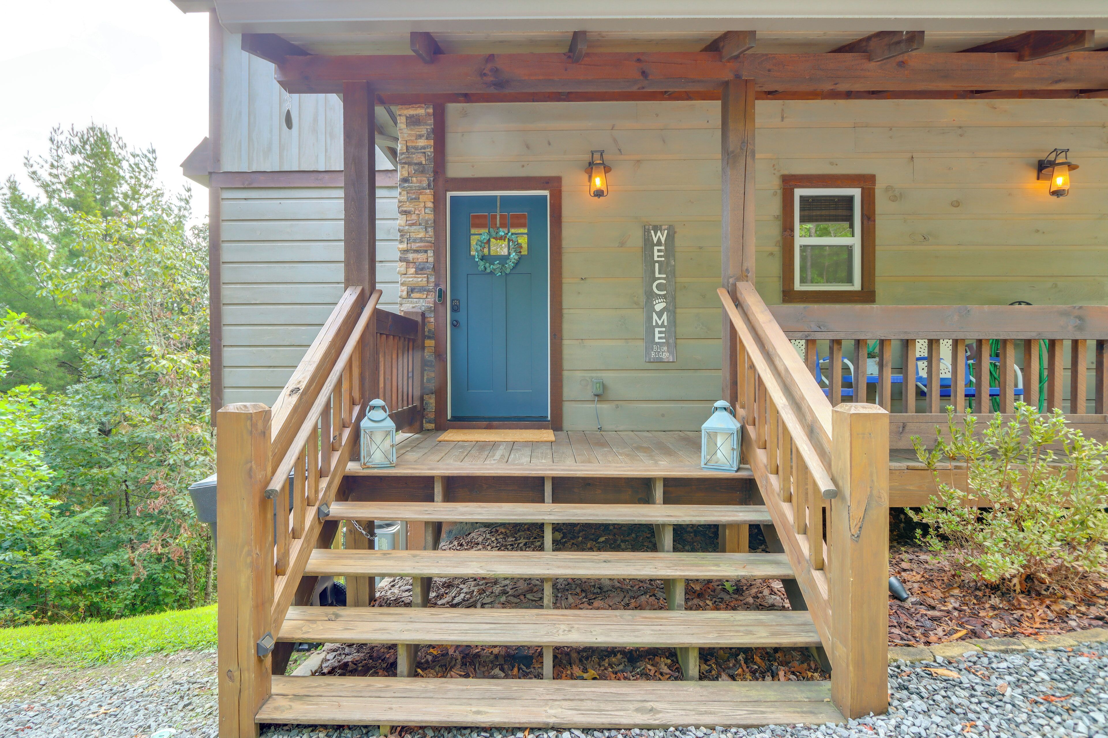 A wooden staircase leading to a front door with a blue door and a 'WELCOME' sign.