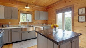 Cocina de cabaña de madera con una isla central, armarios empotrados y un ventanal que proporciona luz natural.
