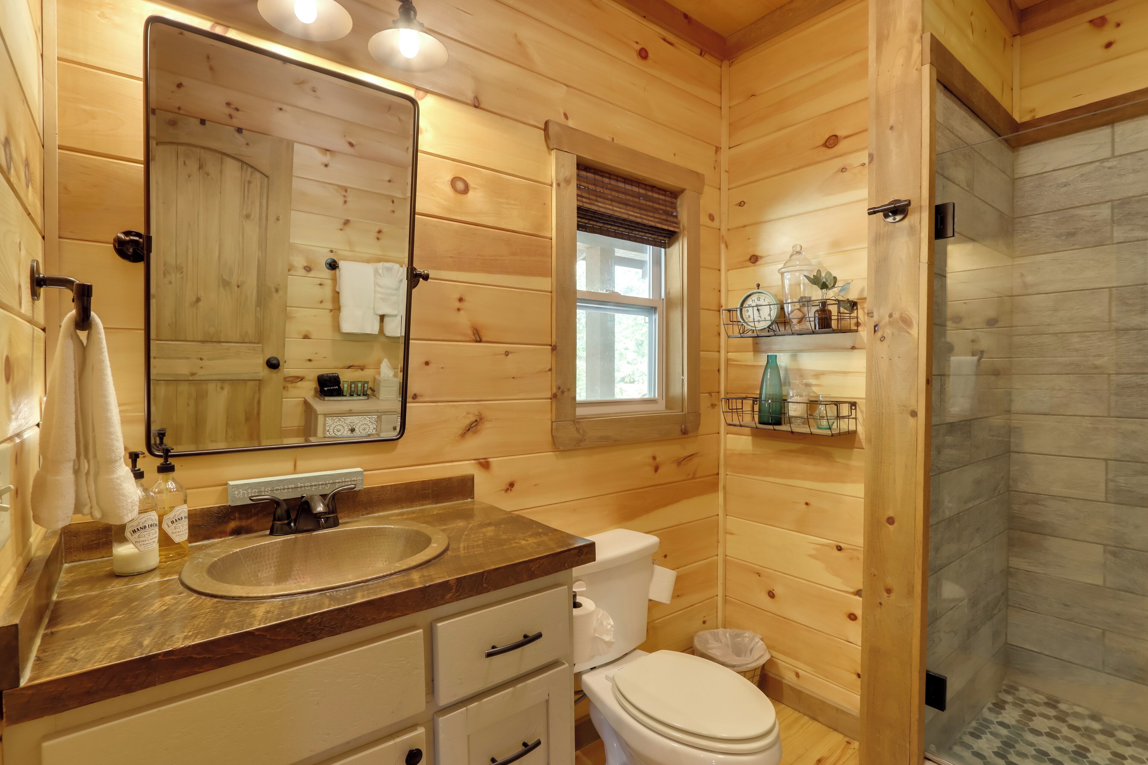 A wooden cabin bathroom with a sink, toilet, and a shower area.