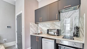 A modern kitchen with dark cabinets, a built-in microwave, a dishwasher, and an oven.