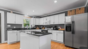 A modern kitchen with white cabinetry, a central island, and a stainless steel refrigerator.