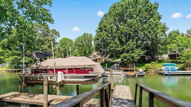A dock with a covered boat, a house, and a swimming area with lounge chairs.