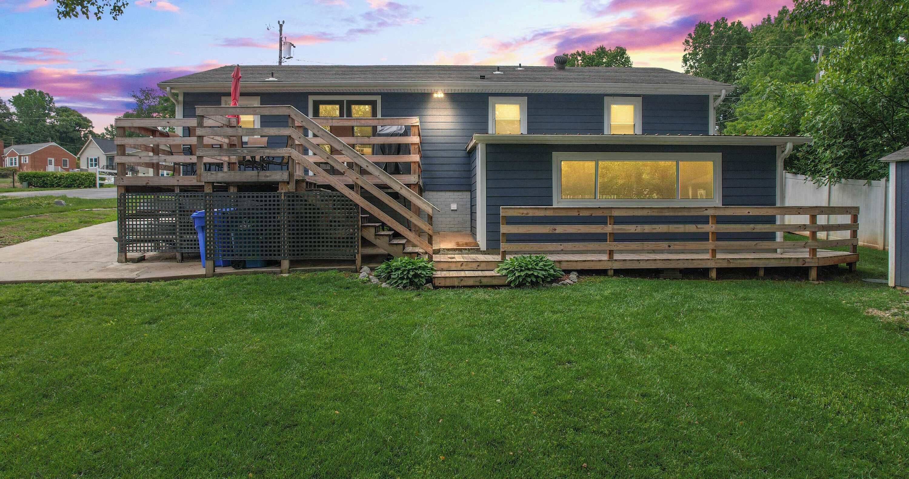 Une maison moderne dotée d’une terrasse en bois, d’un escalier et d’un espace clôturé.