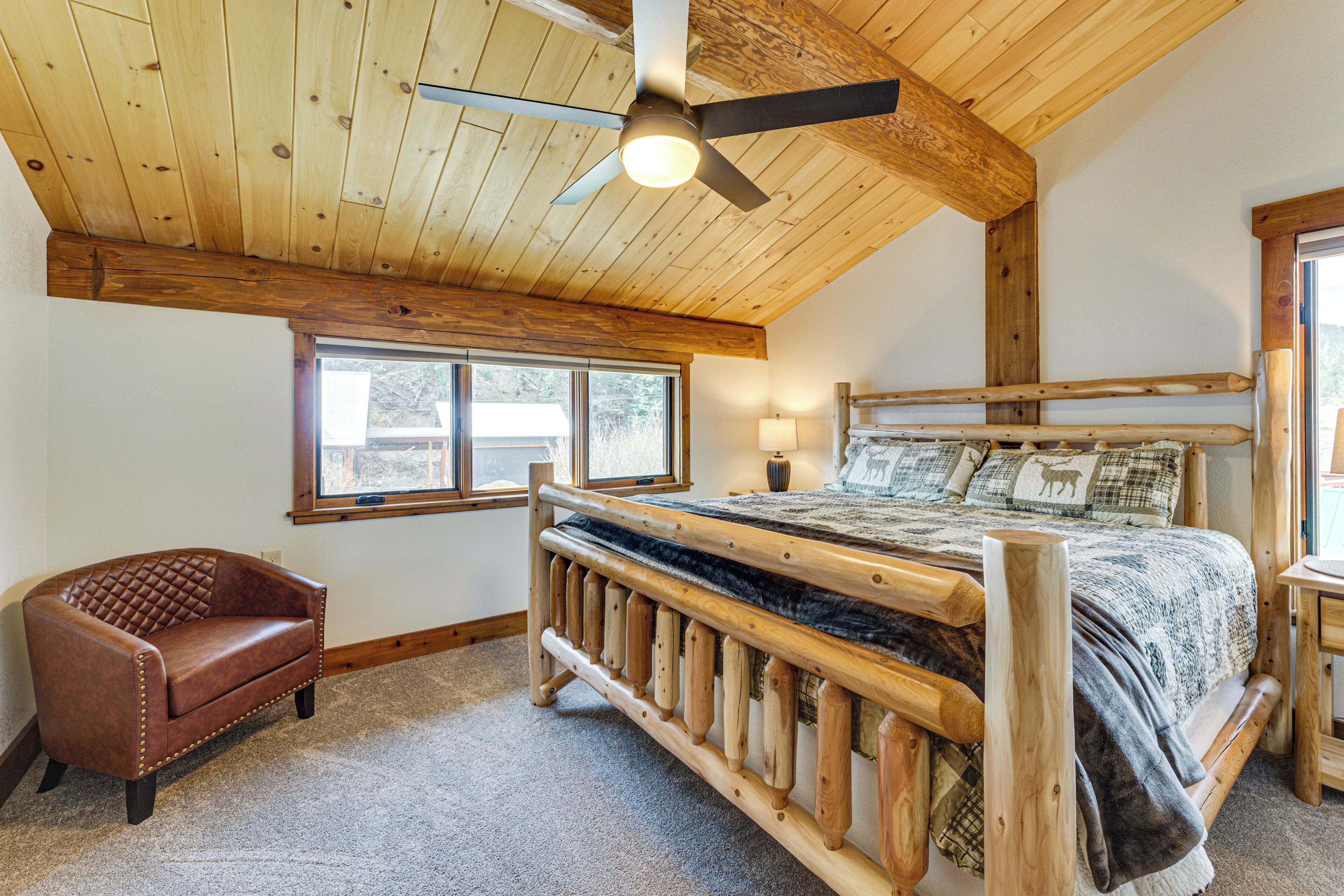 Ein Schlafzimmer mit einem Bettgestell aus Holz, einem Ledersessel und einem Deckenventilator.
