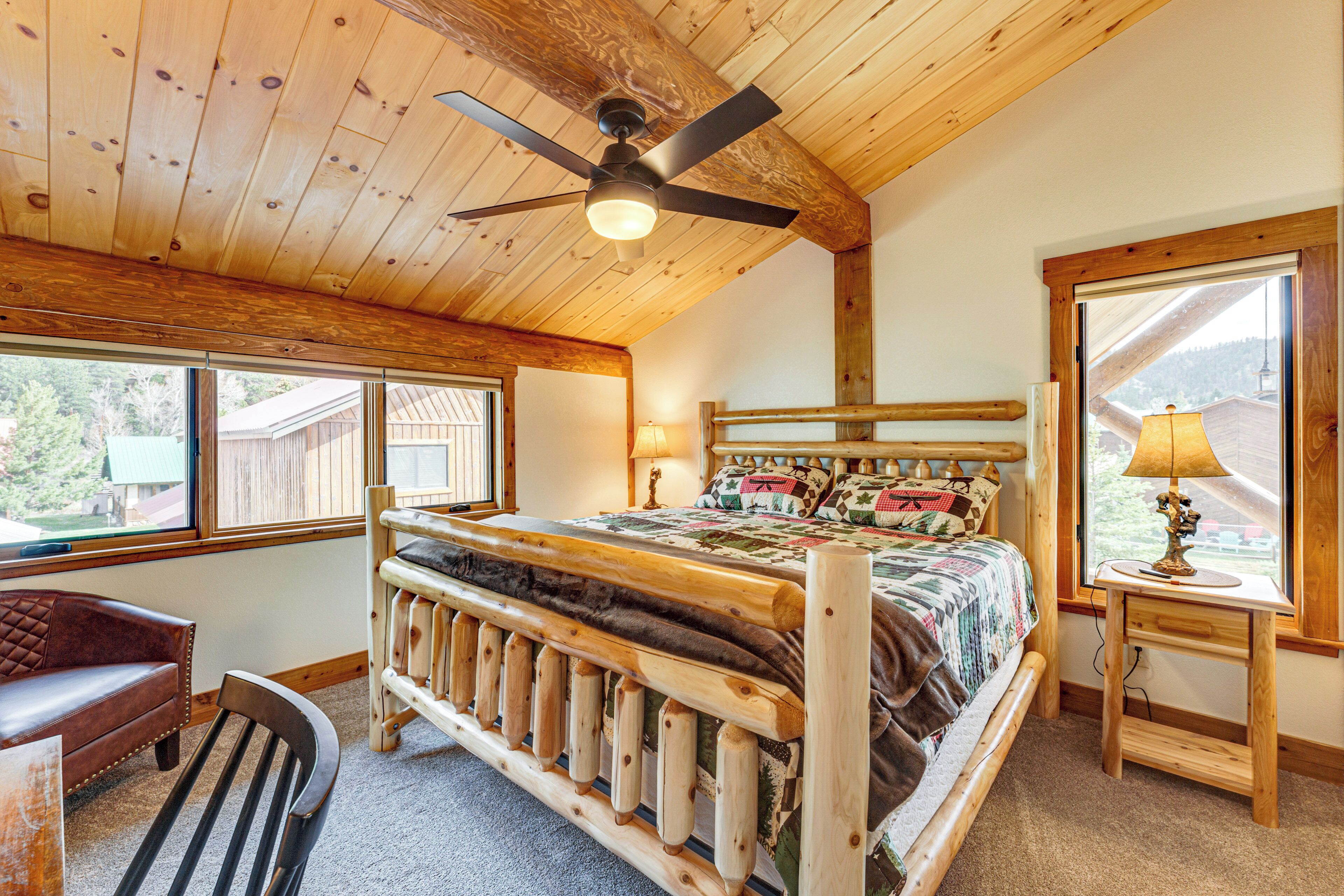 A wooden bedroom with a bed, a chair, a desk, and a window.