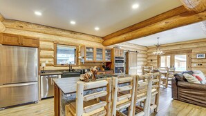 Interior de una cabaña de troncos con cocina, comedor y sala de estar.