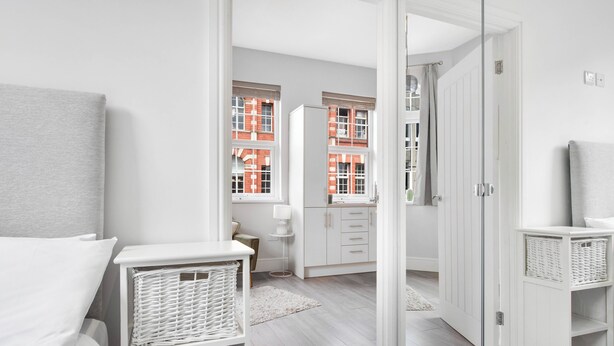 Une chambre à coucher moderne et bien éclairée, avec un lit, des tables de chevet et une armoire.