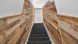 Un escalier en bois dont les marches sont recouvertes de moquette et qui monte.