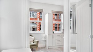 Une pièce moderne et bien éclairée, avec une armoire blanche, un canapé vert et une petite table d’appoint blanche.