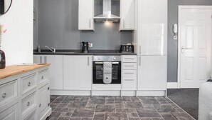 Een moderne keuken met witte kasten, een inbouwoven en een magnetron.