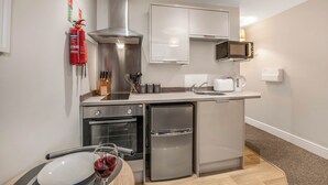 A compact kitchen with stainless steel appliances, a microwave, a coffee maker, and a fire extinguisher on the wall. - WhiskAwayHomes Jenkins House Apartment 2 (Worcestershire)