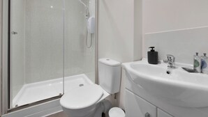 A modern bathroom with a glass-enclosed shower, a white sink with a mirror, and a toilet. - WhiskAwayHomes Jenkins House Apartment 2 (Worcestershire)
