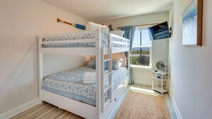 Une chambre avec un lit superpos é, une fenêtre, un ventilateur et un tableau au mur.