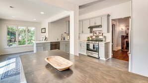A modern kitchen with white cabinetry, a large island, and a view of the outdoors. - Walk to Mcdonough Square: Historic Home w/ Yard! (McDonough)